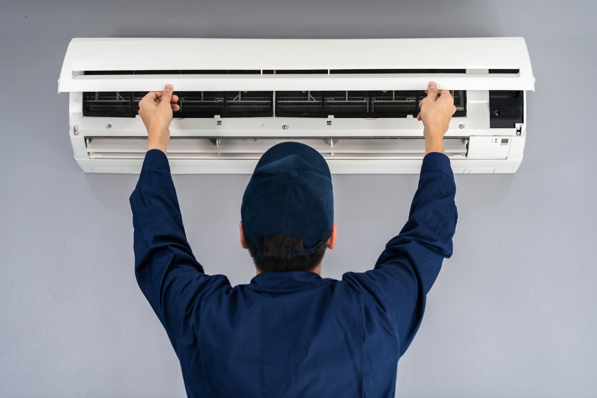 Cooling contractor in uniform installing wall-mounted air conditioner